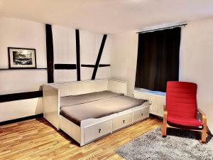 a bedroom with a bed and a red chair at Apartment Weilburg Lahnblick in Weilburg
