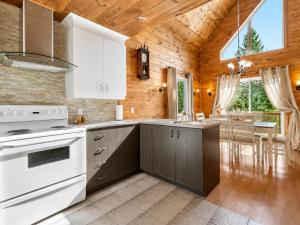 a kitchen with white appliances and a wooden ceiling at Le Malpic in Mont-Laurier