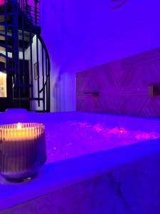 a purple room with a hot tub with a candle at Spa Signature in Dijon