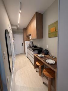 a small kitchen with a table and a refrigerator at 08 Studio com Arte e Sofisticação perto do Consulado in São Paulo