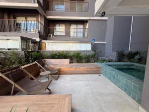 a patio with a swimming pool and chairs and a building at 08 Studio com Arte e Sofisticação perto do Consulado in São Paulo