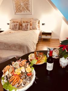 a table with two plates of food and a bottle of wine at L Éden aux hirondelles & SPA in Samer