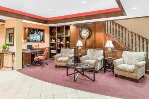 a lobby with chairs and a table and a clock at Ramada by Wyndham Vandalia in Vandalia