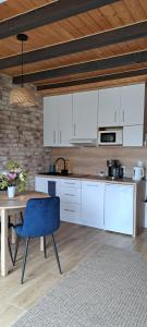 a kitchen with white cabinets and a table with a blue chair at Domki Kapitańskie Lubiatowo z sauną i balią z jacuzzi in Lubiatowo