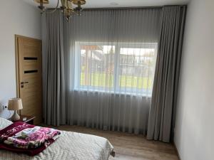a bedroom with a bed and a large window at Luxury Residence Akmenė in Akmenė