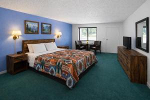a bedroom with a bed and a table with a television at Branding Iron Motel in Chama