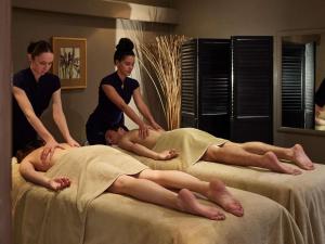 two women helping a man laying on a bed at Sofitel Biarritz Le Miramar Thalassa in Biarritz