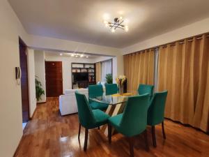 a dining room with a table and green chairs at Amatista Apartment in Cusco
