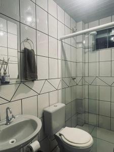 a white bathroom with a toilet and a sink at Hotel Real in Realeza