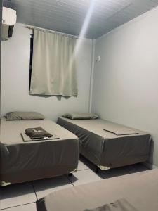 two twin beds in a room with a window at Hotel Real in Realeza