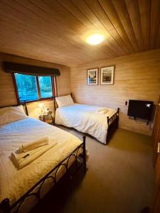 a bedroom with two beds and a flat screen tv at Cosy Log Cabin in Machynlleth - Wales - Wifi & Parking in Machynlleth