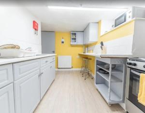a kitchen with white cabinets and a yellow wall at Egremont Hide Away - Perfect contractor accommodation - Close to Sellafield in Woodend +5 photos