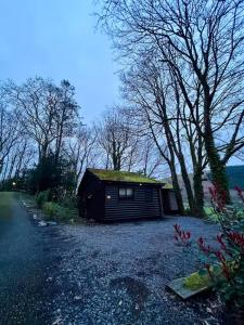a small cabin with a grass roof on a gravel road at Cosy Log Cabin in Machynlleth - Wales - Wifi & Parking in Machynlleth +11 photos