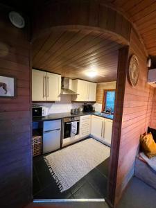 a kitchen with white cabinets and an arched ceiling at Cosy Log Cabin in Machynlleth - Wales - Wifi & Parking in Machynlleth