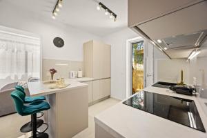 a kitchen with white counters and a green chair at New luxury apartment RABASOL in Rabac
