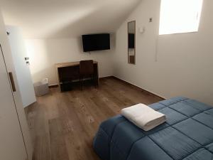 a bedroom with a blue bed and a television at Maison MariEtt - Smart & Living Suites - in Troia