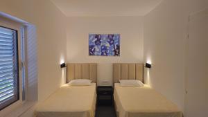 two beds in a room with a painting on the wall at Apartment Rose Garden in Risan