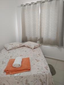 a bed with an orange towel and a shower curtain at EM CASA in Palhoça
