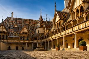a building with a tile roof and a cobblestone street at Appart' Spa et Sauna Privatif Au Cœur De Beaune in Beaune