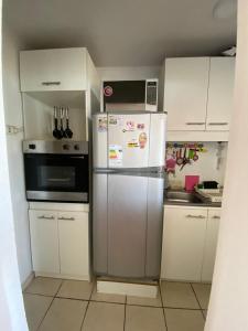 a kitchen with white cabinets and a refrigerator at Condominio María Teresa in Quintero +10 photos