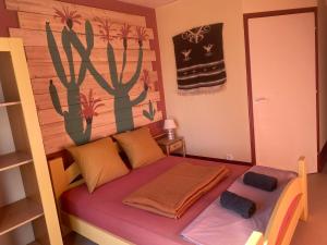 a bedroom with a bed with a cactus painting on the wall at Evasion Latine in Castelnau-Rivière-Basse