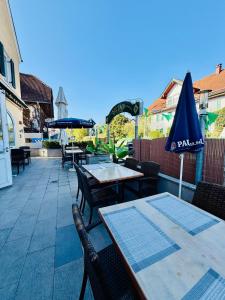 a patio with tables and chairs and an umbrella at Hotel La Strada & Sultan in Murnau am Staffelsee