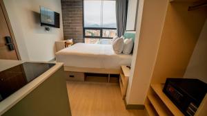 a small bedroom with a bed and a window at CITIO Hotel - Laureles in Medellín