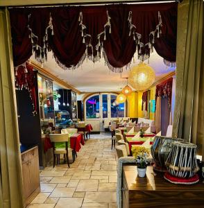 a restaurant with tables and chairs and a chandelier at Hotel La Strada & Sultan in Murnau am Staffelsee