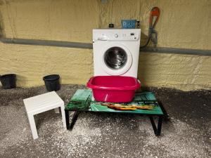 a washing machine with a red bowl next to a stool at Oustau deu Beç in Verdaches