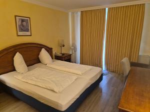 a bedroom with a bed with white sheets and a table at Hotel La Strada & Sultan in Murnau am Staffelsee