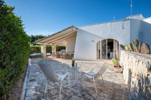 a patio with chairs in front of a white building at Serena Armando Exclusive Villas with Private Pools in Rosa Marina