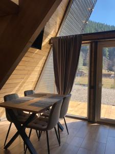 a wooden table and chairs in a room with a large window at Frame&Forest2 in Kolochava