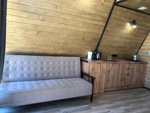 a white couch in a room with a wooden wall at Frame&Forest2 in Kolochava