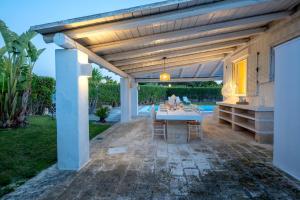 a patio with a table and chairs under a pergola at Serena Armando Exclusive Villas with Private Pools in Rosa Marina