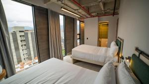 a hotel room with two beds and a large window at CITIO Hotel - Laureles in Medellín +53 photos