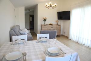 a dining room with a table with plates and wine glasses at Apartamentos Los Novalejos in Arnuero