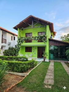 a green house with a lawn in front of it at Chalé Esmeralda in Gravatá