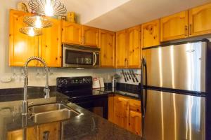 a kitchen with wooden cabinets and a stainless steel refrigerator at 09 Valhalla in Whistler +13 photos