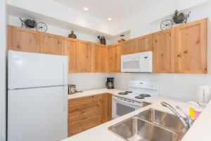a kitchen with wooden cabinets and a white refrigerator at Bright and Clean, Walk Everywhere, Shared Pool and Hot Tub in Whistler