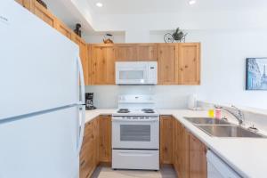 a kitchen with white appliances and wooden cabinets at Bright and Clean, Walk Everywhere, Shared Pool and Hot Tub in Whistler