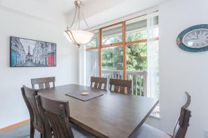 a dining room with a wooden table and a clock at Bright and Clean, Walk Everywhere, Shared Pool and Hot Tub in Whistler