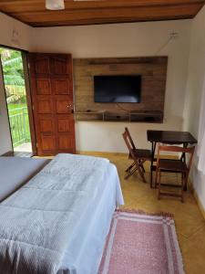 a bedroom with a bed and a table and a tv at Pousada Chalés da Estalagem in São Bento do Sapucaí