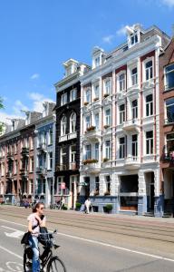 a woman riding a bike down a city street at Museum Lane Hotel in Amsterdam