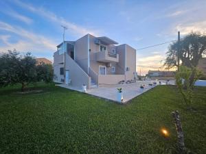 a large white house with a grass yard at Maresia Apts & Studios in Arillas
