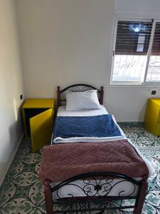 a small bed in a room with a window at Tabriquet urban shared room in Salé