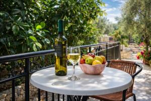 a bottle of wine and a bowl of fruit on a table at Natsios Apartments in Vlachopoulátika