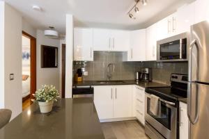 a kitchen with white cabinets and a stainless steel refrigerator at 63 Lagoons in Whistler