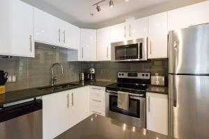 a kitchen with white cabinets and a stainless steel refrigerator at 63 Lagoons in Whistler