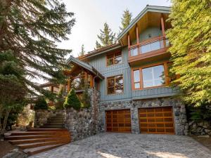 a house with two garage doors and some trees at Luxury 5 Bedroom Blueberry Chalet in Whistler