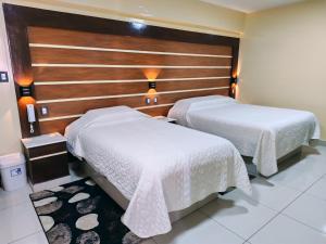 two beds in a hotel room with white sheets at Hostal Face in La Paz